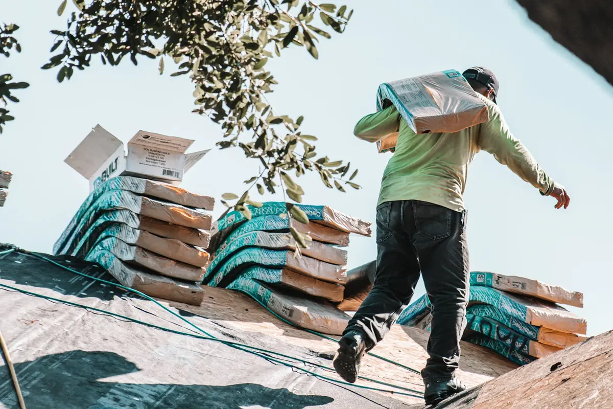 Florida Roof Age Rules for Home Insurance: illustrative photo of a roofer carrying shingles during a reroof